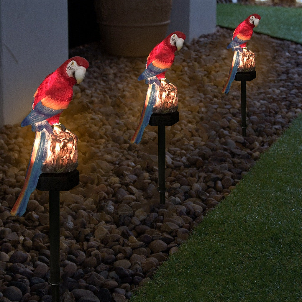 Solar parrot lamp — warm LED light glow at night — garden pathway in use
